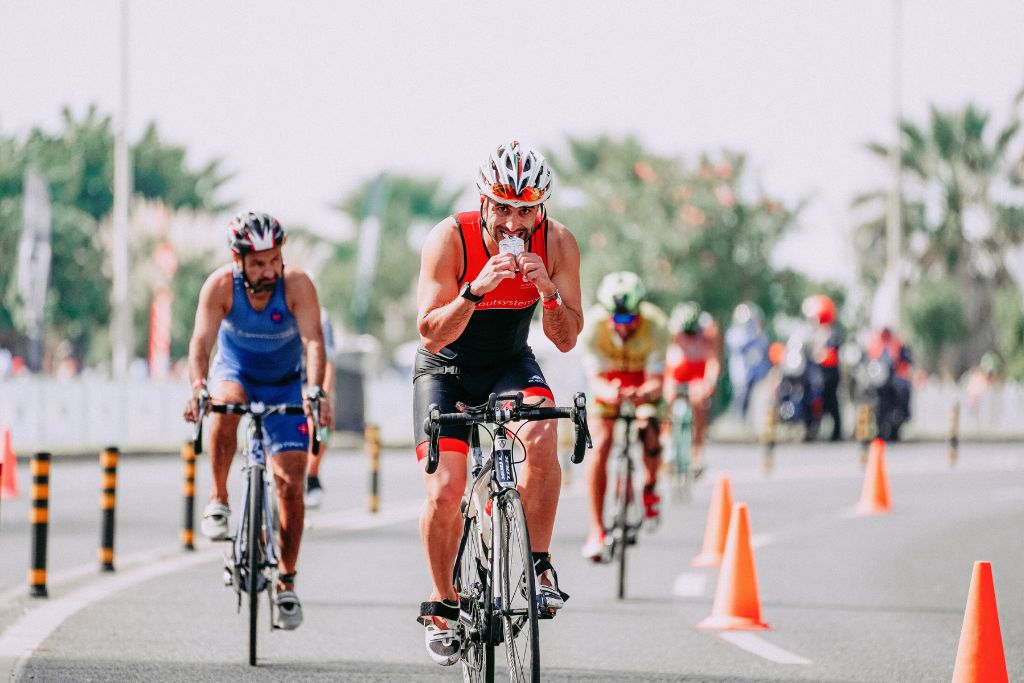 An athlete eating an energy gel on a triathlon bike course.