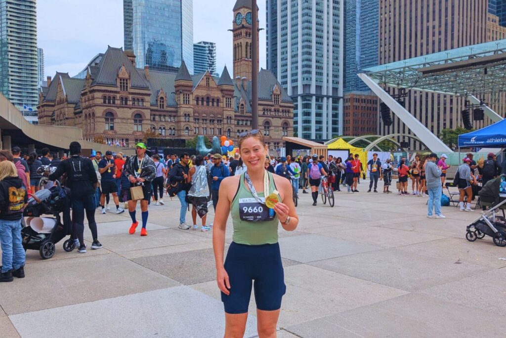 A runner posing with a finisher medal after running a marathon last minute.