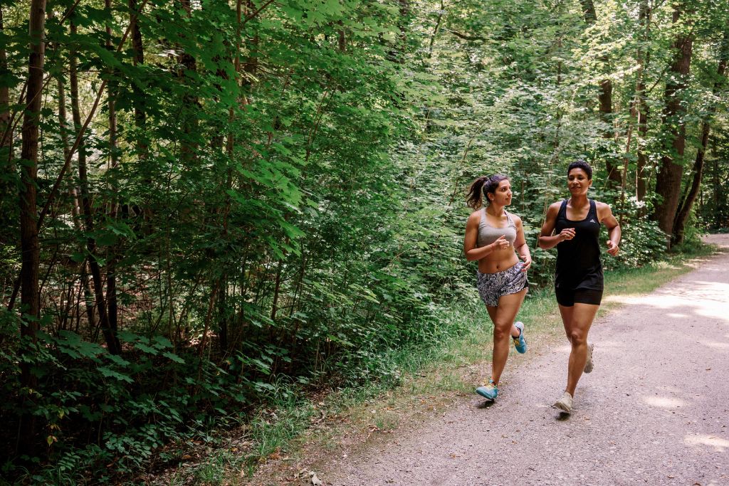 Recovery mistakes runners make: Two female runners running through a forest.