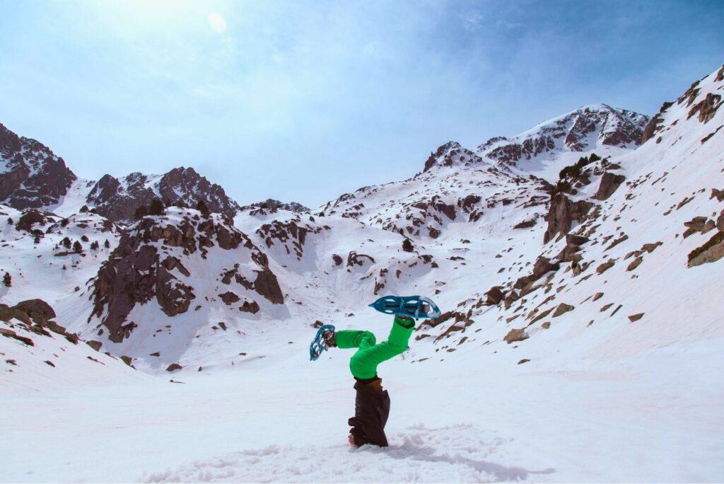 A snowshoer doing a handstand in the snow.