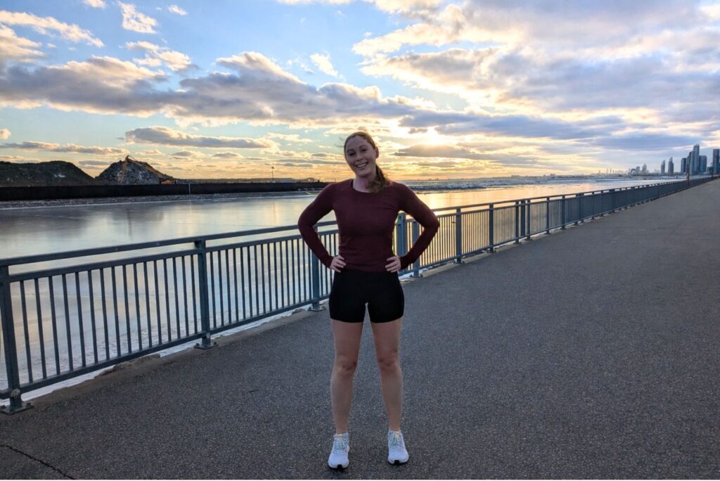 A female runner standing by the waterfront.